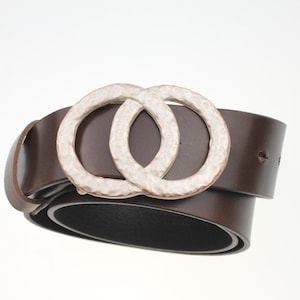May include: A brown leather belt with a silver double circle buckle. The buckle has a hammered texture.