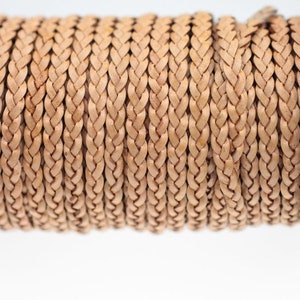 May include: A spool of light brown braided leather cord. The cord is tightly wound around the spool and is ready to be used for crafting projects.