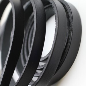 May include: Close-up of black leather straps, showing the texture and detail of the material.