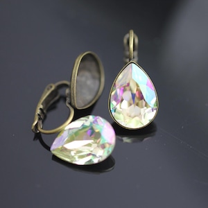 Puede incluir: Un par de pendientes de gota de tono dorado antiguo con piedras de cristal transparentes iridiscentes.
