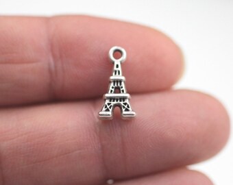 May include: Silver charm in the shape of the Eiffel Tower. The charm is small and detailed, perfect for adding a touch of Parisian style to jewelry.