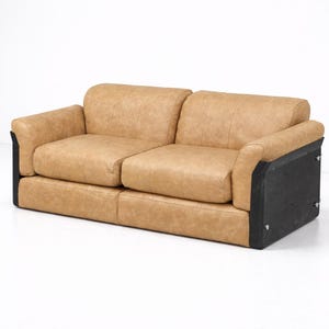May include: A two-seater sofa with a tan leather upholstery. The sofa has a low profile with rounded arms and black side panels. The cushions appear soft and inviting, perfect for a living room or lounge area.