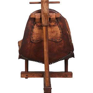 May include: A wooden chair with a brown leather seat and a wooden frame. The chair has a unique design with a tall back and a wide seat.