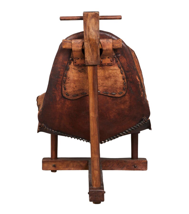 May include: A wooden chair with a brown leather seat and a wooden frame. The chair has a unique design with a tall back and a wide seat.