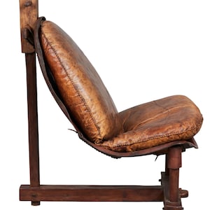 May include: A brown leather armchair with a wooden frame. The chair has a unique design with a curved back and a wide seat.