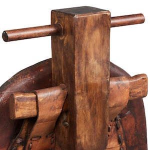 May include: A wooden stool with a brown leather seat. The stool has a wooden handle on the back and is made of natural wood.