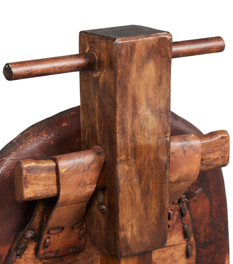 May include: A wooden stool with a brown leather seat. The stool has a wooden handle on the back and is made of natural wood.