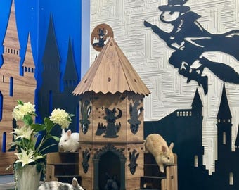 May include: A wooden rabbit hutch with a castle design, featuring a multi-tiered structure and decorative cutouts. Several rabbits of different colors are inside and around the hutch. The background includes castle silhouettes and a witch-themed wall decoration.