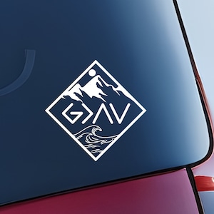 May include: White vinyl decal with a diamond shape. The decal features a mountain range with a sun and the words "God is Greater Than" in a stylized font. The bottom of the decal features waves.