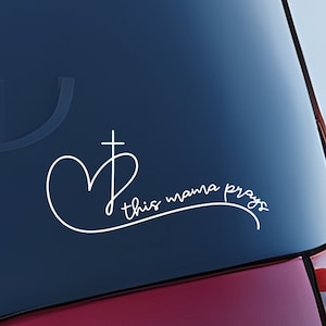 May include: White vinyl decal with a heart and cross design and the text "this mama prays".