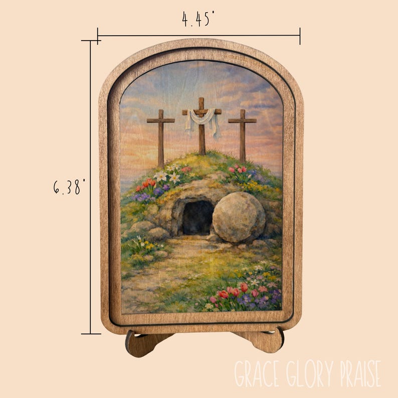 May include: An arched wooden frame containing a printed illustration of three crosses on a hill above a stone tomb with a rolled-away stone. The frame measures 4.45 inches wide by 6.38 inches high. The scene features colorful flowers and a sky.