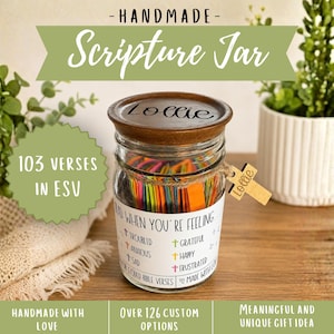May include: A clear glass jar with a dark wooden lid engraved with the name Lollie. The jar contains colorful paper slips and features a label reading "Glad when you're feeling..." with categories like troubled, anxious, sad, grateful, happy, and frustrated. A small wooden cross tag labeled Lollie is attached.