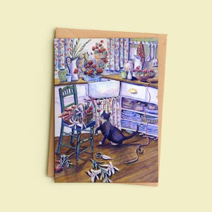 May include: A rectangular greeting card featuring a colourful illustration of a kitchen scene with a black and white cat playing with a long string. The kitchen includes a green chair, a white sink, floral curtains, and various potted flowers.