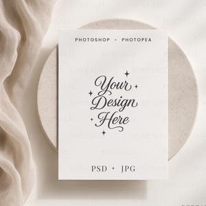 May include: A white card with the text "Your Design Here" in elegant script, resting on a beige plate. The words "PHOTOSHOP + PHOTOPEA" and "PSD + JPG" are also visible. A soft, draped fabric is in the background.