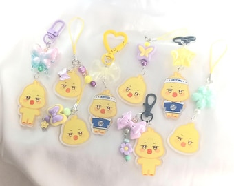 May include: A set of nine colorful keychains featuring cartoon yellow chicks with different expressions. Each keychain has a variety of charms, including butterflies, flowers, and bows. The keychains are made of plastic and are perfect for adding a touch of whimsy to your keys or bag.