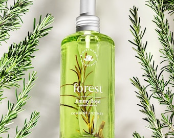 May include: A clear glass bottle of "forest" cologne by Jimmy Boyd. The bottle is filled with a green liquid and has a silver spray nozzle. The bottle is surrounded by sprigs of rosemary.