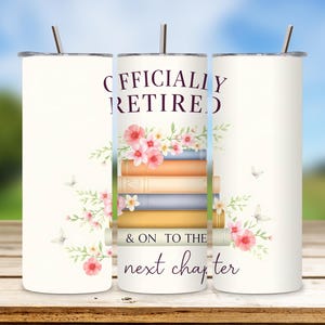 May include: A white tumbler with a straw, featuring the text "OFFICIALLY RETIRED" and "& ON TO THE next chapter" in a script font. The design includes a stack of books, pink flowers, and butterflies.