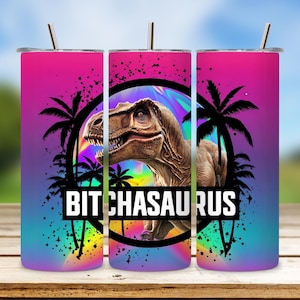 May include: A pink, purple, and blue ombre tumbler with a black and white graphic of a dinosaur with palm trees and the text "Bitchasaurus".