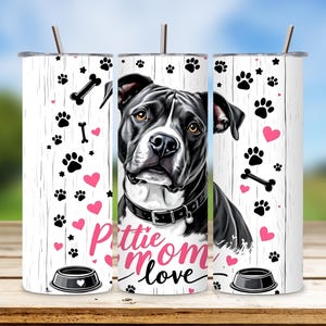 Puede incluir: Un vaso blanco con una ilustración de un perro pit bull blanco y negro. El vaso tiene un diseño de corazón rosa y huella de pata y el texto "Pittie Mom Love".