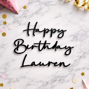 May include: A marble background with the words "Happy Birthday Lauren" in black script. The image includes party decorations such as a pink party hat, gold confetti, a gold star wand, and pink and gold accents.