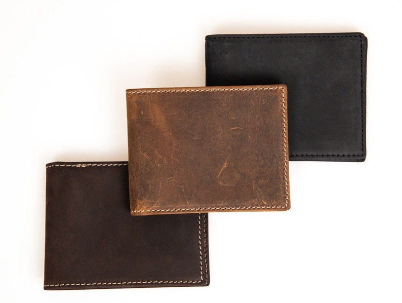 May include: Three leather wallets in different shades of brown. The top wallet is a light brown, the middle wallet is a medium brown, and the bottom wallet is a dark brown.