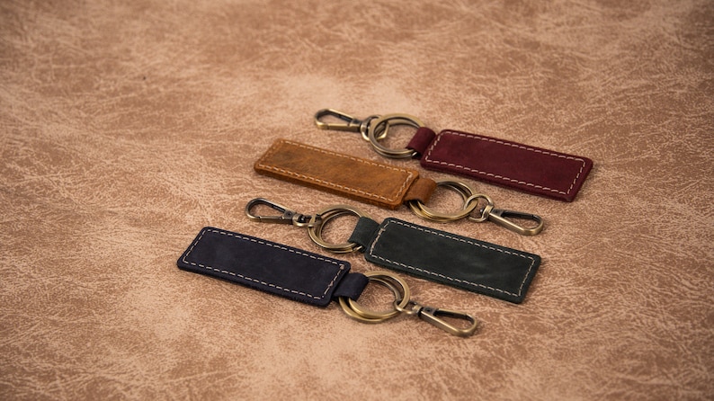 K&ouml;nnte beinhalten: Vier Leder-Schl&uuml;sselanh&auml;nger mit Metallringen und -verschl&uuml;ssen. Die Schl&uuml;sselanh&auml;nger sind in verschiedenen Farben: Braun, Burgunderrot, Dunkelblau und Dunkelgr&uuml;n.