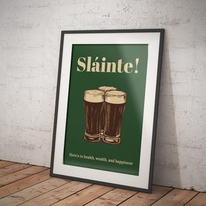 Może przedstawiać: Zielony plakat z tekstem "Sl&aacute;inte!" w ż&oacute;łtym kolorze. Trzy szklanki ciemnego piwa ułożone są w kształcie tr&oacute;jkąta. Tekst "Here's to health, wealth, and happiness" znajduje się na dole plakatu.