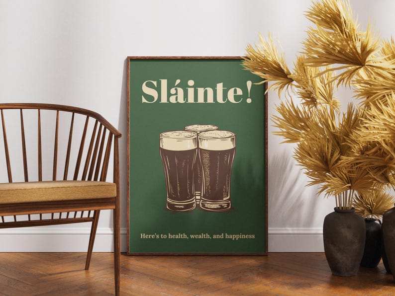 Może przedstawiać: Zielony plakat z tekstem "Sl&aacute;inte!" w kolorze białym i grafiką trzech szklanek ciemnego piwa. Tekst pod szklankami brzmi "Here's to health, wealth, and happiness."