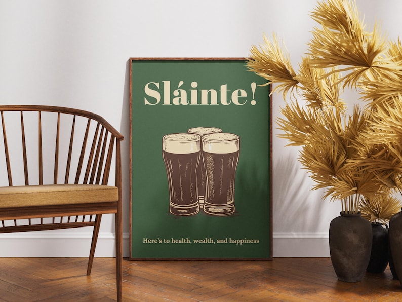 May include: A green poster with the text "Sl&aacute;inte!" in white and a graphic of three glasses of dark beer. The text below the glasses reads "Here's to health, wealth, and happiness."