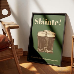 Może przedstawiać: Zielony plakat z tekstem "Sl&aacute;inte!" w ż&oacute;łtym kolorze. Trzy szklanki ciemnego piwa są ułożone jedna na drugiej. Tekst "Here's to health, wealth, and happiness" znajduje się na dole plakatu.