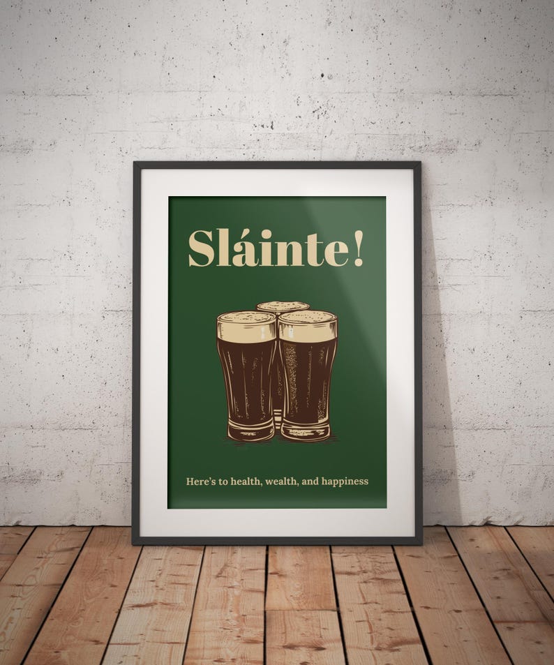 Może przedstawiać: Wydruk w ramie z zielonym tłem i tekstem "Sl&aacute;inte!" w kolorze ż&oacute;łtym. Trzy szklanki ciemnego piwa ułożone są w kształcie tr&oacute;jkąta. Tekst "Here's to health, wealth, and happiness" znajduje się na dole wydruku.