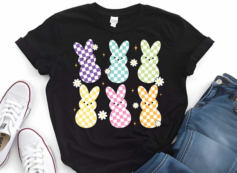 Puede incluir: Camiseta negra con un gr&aacute;fico de seis conejos con cuadros pastel con flores y estrellas blancas.