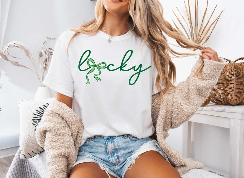 May include: White t-shirt with the word "lucky" written in green cursive with a green bow in the "c".
