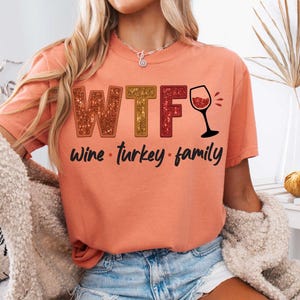 May include: A peach colored t-shirt with the text "WTF Wine - Turkey - Family" and a glass of wine graphic.