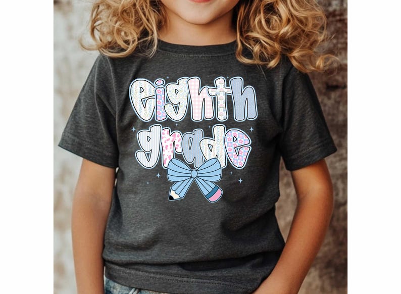 Pu&ograve; includere: T-shirt grigio scuro di "Eighth Grade" con un design colorato. Il testo "Eighth Grade" &egrave; in un font a bolle con accenti floreali e pastello. Un fiocco azzurro e una matita adornano la parte inferiore del testo.