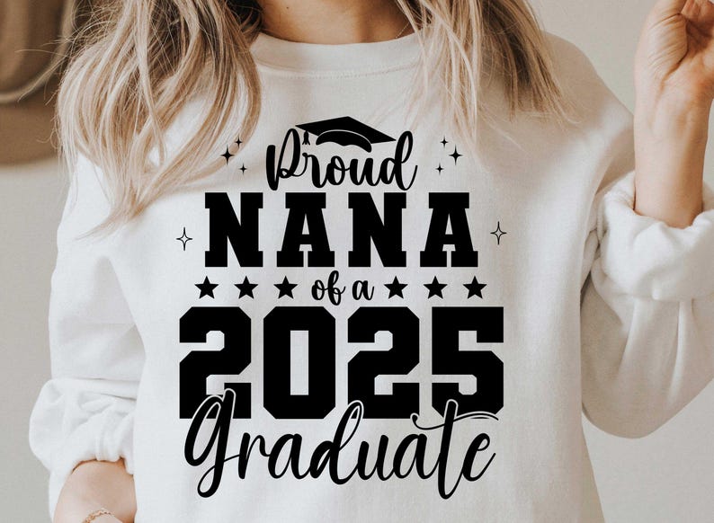K&ouml;nnte beinhalten: Wei&szlig;er Pullover mit schwarzem Text, der "Proud Nana of a 2025 Graduate" lautet.