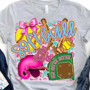 May include: A gray t-shirt with a pink, blue, and yellow softball design. The design includes a softball, bats, a glove, a helmet, and a home plate. The text "Softball" is written in blue and pink letters. The text "3 Up 3 Down" is written in black letters. The text "Hey Batter Batter" is written in green letters.