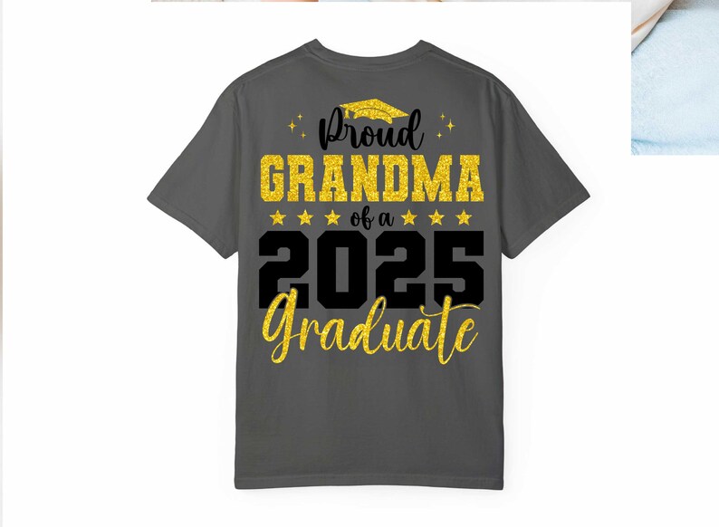 K&ouml;nnte beinhalten: Ein dunkelgraues T-Shirt mit goldfarbenem Glitzertext, auf dem "Proud Grandma of a 2025 Graduate" steht.