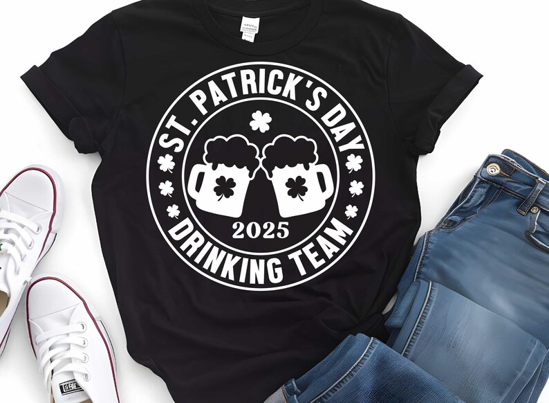 May include: Black t-shirt with a white circle graphic that says "St. Patrick's Day Drinking Team 2025" with two beer mugs and shamrocks.