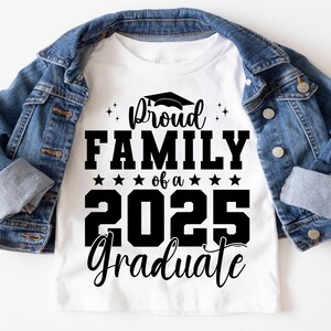K&ouml;nnte beinhalten: Wei&szlig;es T-Shirt mit schwarzem Text, der "Proud Family of a 2025 Graduate" lautet, mit einem Grafikbild eines Abschluss-Hutes &uuml;ber dem Wort "Proud".