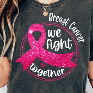 May include: A black t-shirt with a pink glitter ribbon and the text "Breast Cancer We Fight Together".