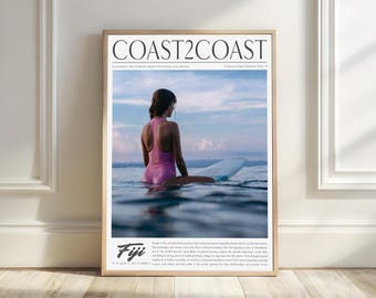 May include: A magazine cover featuring a woman in a pink swimsuit surfing on a white surfboard in the ocean. The magazine is titled "Coast2Coast" and the cover features the text "Fiji" with the coordinates 17.7134° S, 178.0650° E.