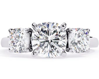 Può includere: Un anello di fidanzamento a tre pietre con un grande diamante rotondo centrale e due diamanti rotondi più piccoli su entrambi i lati. L'anello è incastonato su una fascia in metallo bianco.
