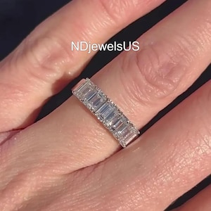 Puede incluir: Primer plano de un anillo con múltiples diamantes de talla rectangular colocados en fila. El anillo está en un dedo. El texto "NDjewelsUS" es visible.
