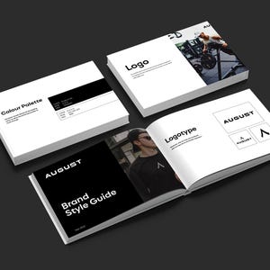 May include: A brand style guide with the word "AUGUST" on the cover, along with a "Color Palette" and "Logo" booklet. The open book displays "Logotype" and a photo of a person. The background is a dark gray.