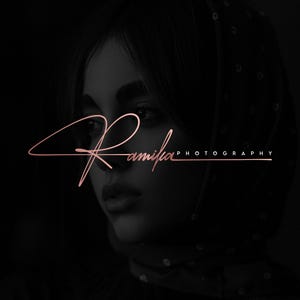 May include: A black and white image of a woman's face with a pink signature that reads "Ramila Photography" below it.