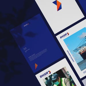 May include: A corporate branding presentation featuring the SHIGR logo and the words "Seamless Logistics." The design incorporates a navy blue and orange color scheme, with images of cargo ships and workers. The layout includes various documents and promotional materials.