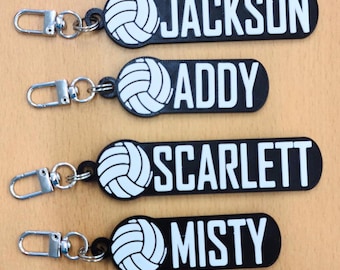 May include: Black keychains with white text and a volleyball graphic. Each keychain has a different name: Lorenzo, Jackson, Addy, Scarlett, Misty, and Emily. The keychains have a silver clasp.