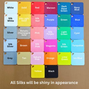 May include: A color chart featuring a variety of square color swatches, each labeled with a different color name. Colors include white, gold, red, maroon, dark aqua green, and navy blue. The text at the bottom reads, "All Silks will be shiny in appearance."