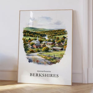 May include: A framed vertical art print featuring a watercolor landscape of a rural town in the Berkshires, Massachusetts. The scene depicts a white church, houses, a winding river, and a covered bridge amidst autumn foliage and green hills.